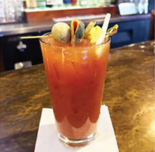 Smokehouse Bloody Mary beverage in a tall glass with an olive and straw 
