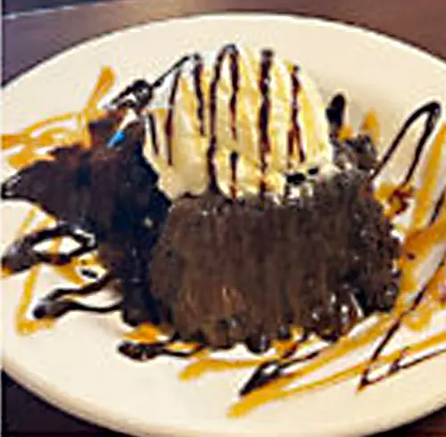 Chocolate Sundae Cake on a plate with ice cream and chocolate drizzle on top 