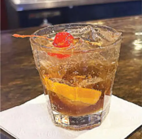 Old Smokey cocktail in a short glass with an orange slice and a cherry on top 