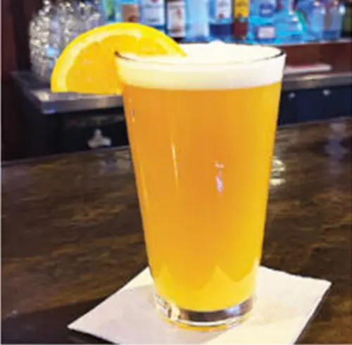 Peach Moon beverage in a tall glass with an orange wedge 
