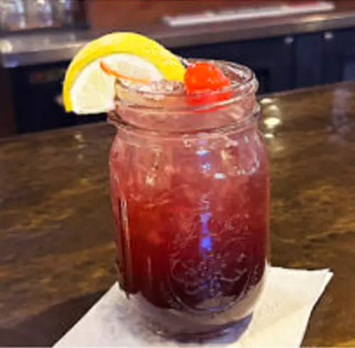 Ruby Red Sangria drink in a Mason jar with a cherry and lemon wedge 