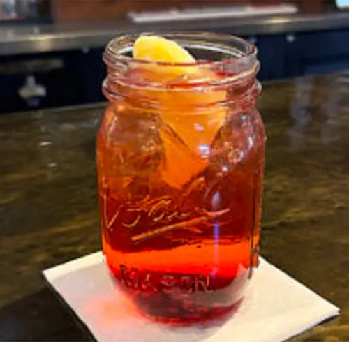 Peach Sangria beverage in a Mason jar with an orange slice 
