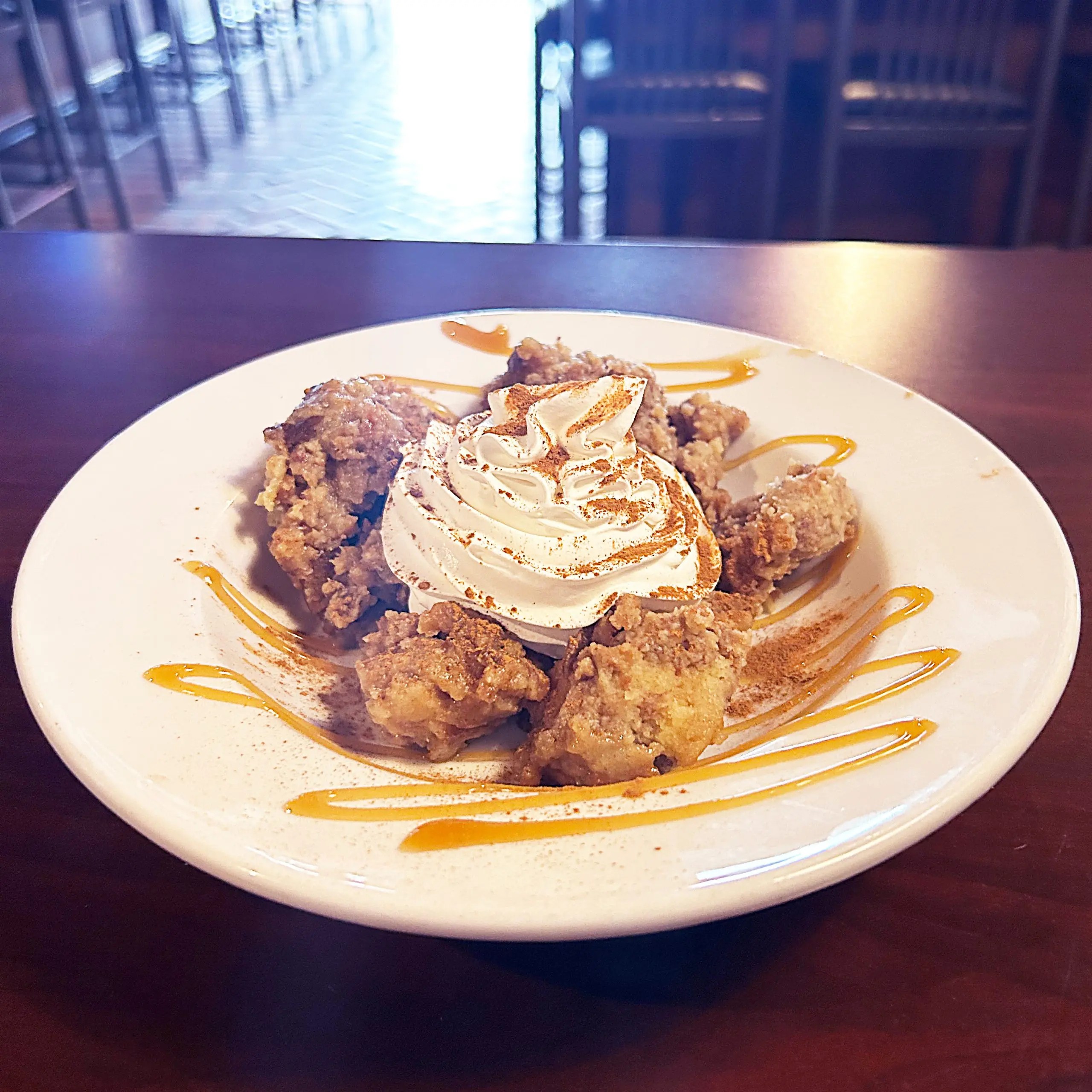 Vanilla Cinnamon Bread Pudding dessert on a plate with caramel drizzle on top 